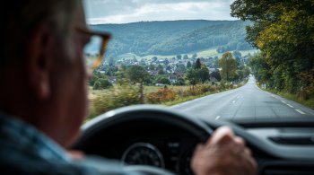 A driver's license and reading glasses resting on a newspaper with medical-related articles.